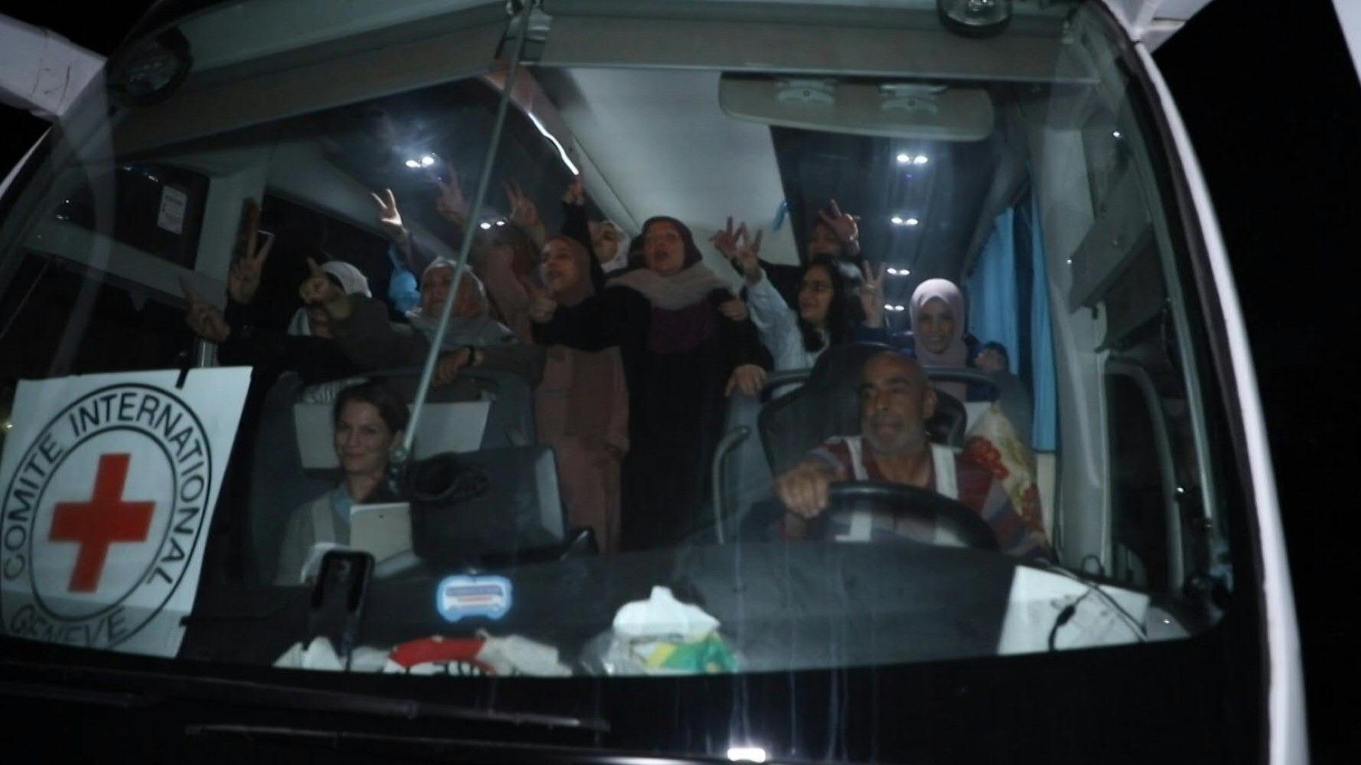 Crowd cheers as an ICRC bus carries prisoners released from Ofer prison in the West Bank