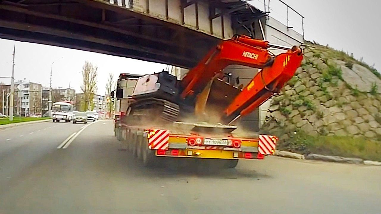 Video: Truck carrying excavator gets wedged under bridge after misjudging height