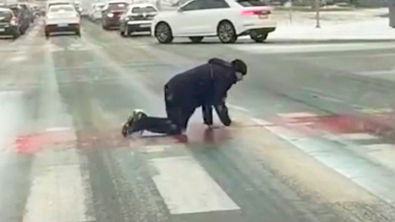 Video: Slippery streets force man to crawl across crosswalk