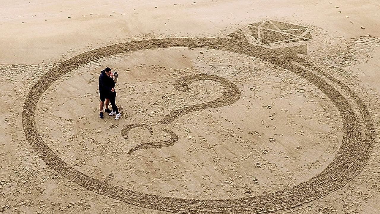 Video: Man has giant ring carved into sand to propose to girlfriend at the beach